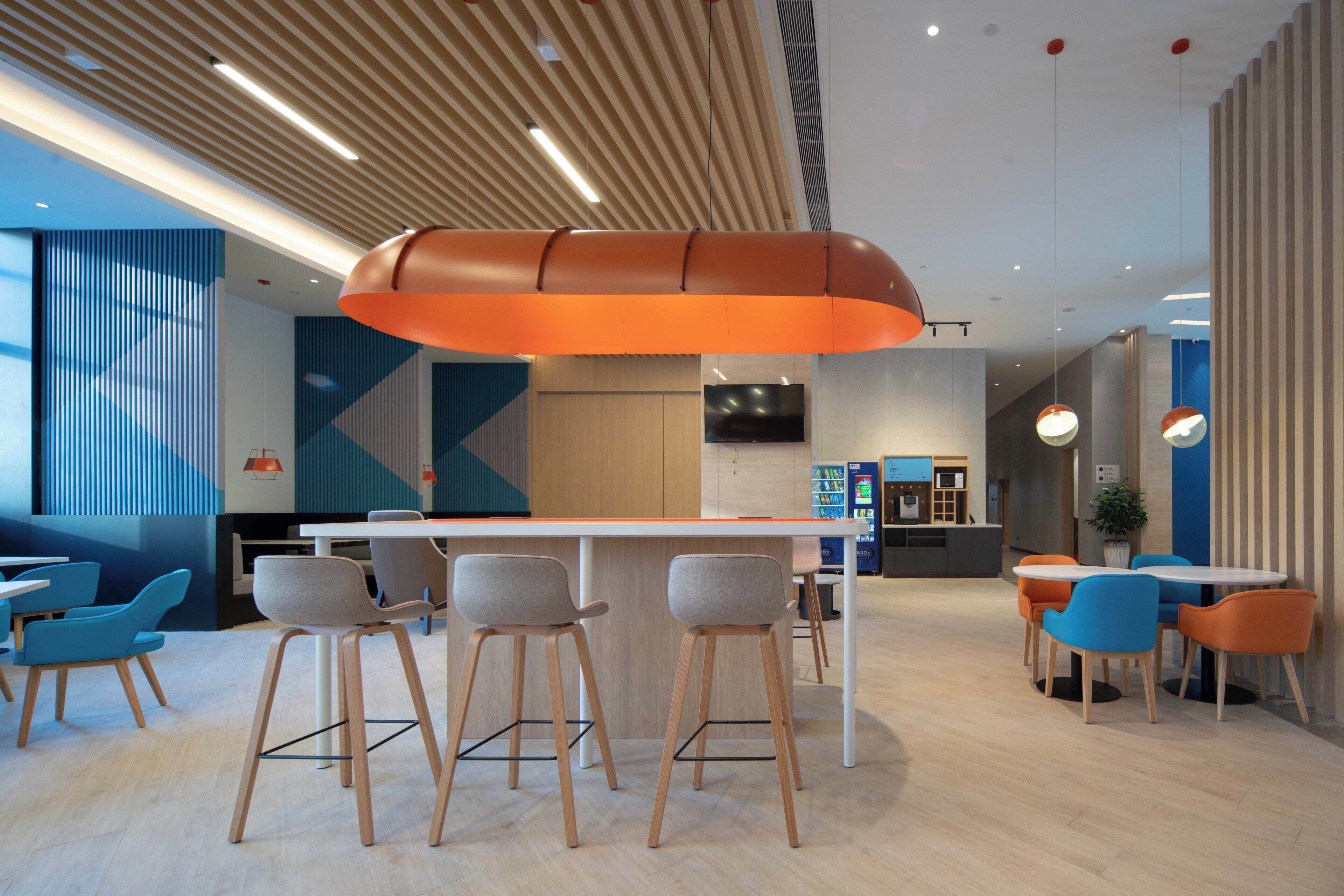 A modern interior with a central bar area, seating arrangements, and a kitchen in the background.