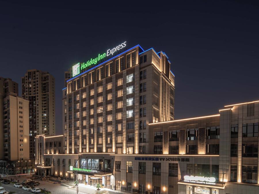 Un hotel de varios pisos con un letrero llamativo que dice 'Holiday Inn Express', un restaurante en la planta baja y un estacionamiento.