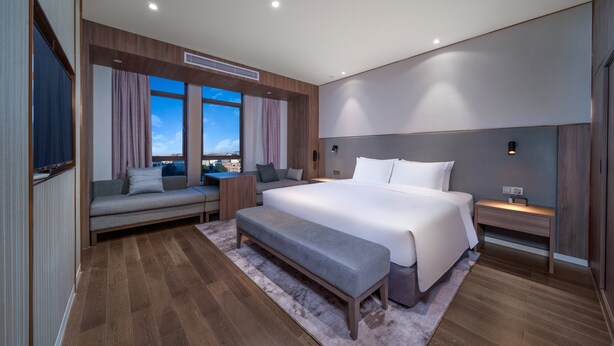 A modern bedroom with a large bed, a bench, a sofa, and a desk. - Holiday Inn Express Jinjiang Anhai by IHG (Quanzhou)