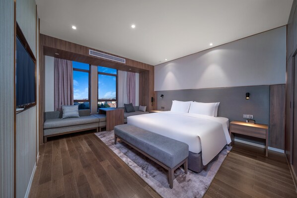 Une chambre moderne avec un grand lit, un banc, un canapé et un bureau.