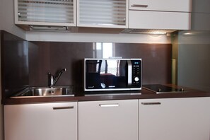 A kitchen with a microwave, a sink, and cabinets. - UR-NEST Rizzoli 2 piano (Bologna)