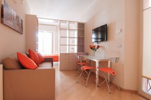A compact living space with a sofa, dining table, chairs, a TV, and a window. - UR-NEST Rizzoli 2 piano (Bologna)
