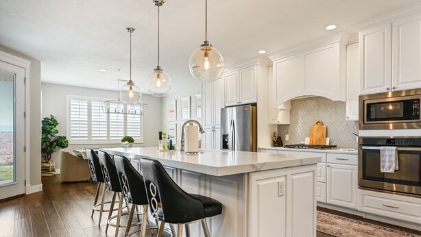A modern kitchen with white cabinetry, a large island with bar stools, stainless steel appliances, and pendant lighting. - Le Château at Las Palmas Resort - The nicest unit in the community!! (St. George)