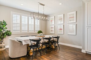 A dining area with a table set for six, surrounded by black chairs, a chandelier, and framed artwork on the walls. - Le Château at Las Palmas Resort - The nicest unit in the community!! (St. George)