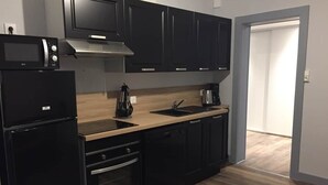 Une cuisine moderne avec des appareils électroménagers noirs, un plan de travail en bois et des meubles de rangement sombres.