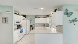 Una cocina moderna con muebles blancos, una isla central y decoración con mariposas en la pared.