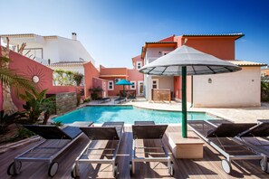 A poolside area with lounge chairs, a pool, and a building with a red and white facade. - Guesthouse D. Manuel I - Adults only (Lagos)
