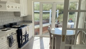 Une cuisine avec des meubles blancs, une cuisinière et un coin repas comprenant une table et des chaises.