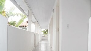 Un couloir aux murs blancs et au sol carrelé, qui mène à une porte.