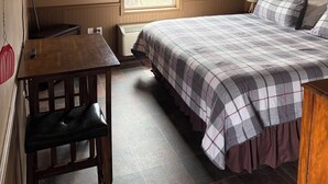 Quarto com cama, escrivaninha, cadeira, janela e radiador.
