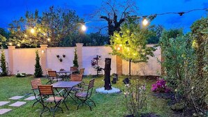 Eine Terrasse mit Tisch und Stühlen, umgeben von einer weißen Mauer und Bäumen.