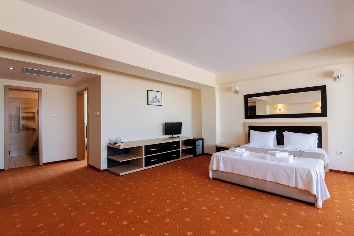 A hotel room with a bed, a TV, a desk, and a wardrobe.