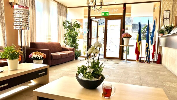 Eine Hotelhalle mit Rezeption, einer Couch, Topfpflanzen und einem Couchtisch mit einer Tasse Tee.