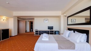 Ein Hotelzimmer mit einem großen Bett, einem Fernseher, einem Schreibtisch und einem Spiegel.