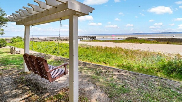 A wooden swing set under a pergola with a view of a beach and a pier. - Oceanfront Sunrises on Mitchelville Beach (Hilton Head Island)