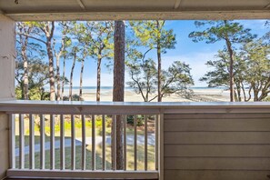 A balcony with a view of a beach and trees.