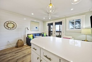 A modern kitchen with a large island, white cabinetry, and a ceiling fan.