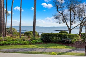 A coastal landscape with a grassy area, trees, and a view of the sea.