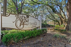 A wooden sign with 'The Foia On Port Royal Sound' written on it, surrounded by trees and shrubs.