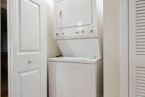 A compact, white, wall-mounted washer and dryer unit with a control panel featuring multiple knobs and a small display. - Soundfront Stay Beach, Pools & More at The Spa (Hilton Head Island)
