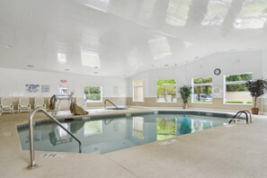 An indoor swimming pool with a lifeguard chair, a pool ladder, and a clock on the wall. - Soundfront Stay Beach, Pools & More at The Spa (Hilton Head Island)