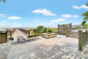 A wooden deck with a bench and a trash bin, leading to a beach. - Soundfront Stay Beach, Pools & More at The Spa (Hilton Head Island)