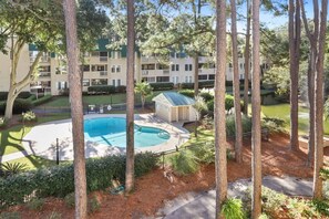 A residential area with a swimming pool, a small building, and a multi-story apartment complex.