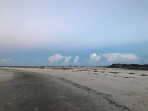 A wide, open sandy area with a clear sky and distant buildings. - Soundfront Stay Beach, Pools & More at The Spa (Hilton Head Island)