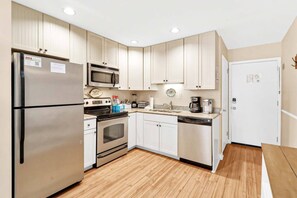 A compact kitchen with a refrigerator, microwave, stove, oven, and dishwasher.