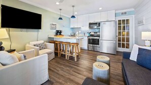 Una cocina moderna con armarios blancos, electrodomésticos de acero inoxidable y una zona de bar con taburetes.