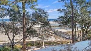 Vista de una playa con un paseo de madera, árboles y un banco.