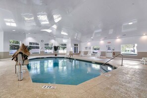 An indoor swimming pool with clear water, a lifeguard chair, and a no diving sign.