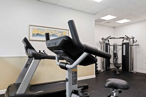 A gym with cardio equipment, weight machines, and a bench.