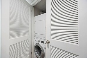 Ein heller Waschraum mit einer Waschmaschine mit Frontlader und einem geschlossenen Trockner.