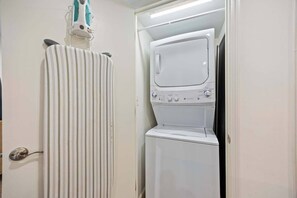 A laundry room with a washing machine and dryer, a striped curtain, and a door handle.