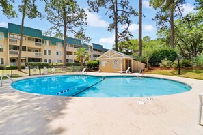 Une piscine dotée d’un poste de surveillance pour les sauveteurs, entourée d’immeubles d’habitation et d’arbres.