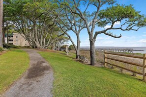 Un sentier qui mène à une plage, avec un banc en bois et une jetée en arrière-plan.