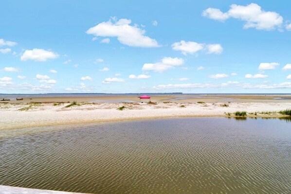 Une plage avec une étendue d’eau calme, une tente rose et un ciel dégagé.