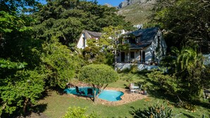 A residential property with a swimming pool, surrounded by lush greenery and a mountainous backdrop. - ZenCapeTown Holiday House (Cape Town)