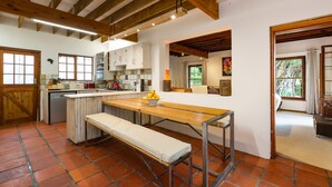 A kitchen with a wooden bench, white cabinets, and a tiled floor. - ZenCapeTown Holiday House (Cape Town)