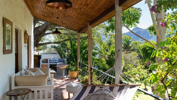 A hammock under a wooden pergola, a white sofa, and a barbecue area with a view of mountains. - ZenCapeTown Holiday House (Cape Town)