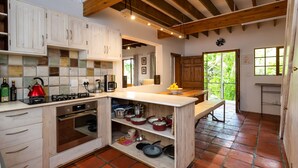 A kitchen with wooden cabinets, a central island, and a tiled floor. - ZenCapeTown Holiday House (Cape Town)