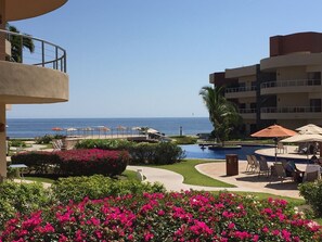 A resort with a pool, lounge chairs, and a view of the ocean.