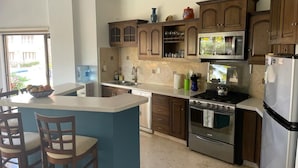 Una cocina con una isla central, armarios de madera, electrodomésticos de acero inoxidable y un reloj en la pared.