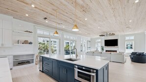 Una cocina moderna con una isla grande, electrodomésticos integrados y un comedor con chimenea.