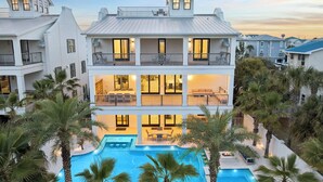 Un hotel de varios pisos con piscina, balcones y palmeras.
