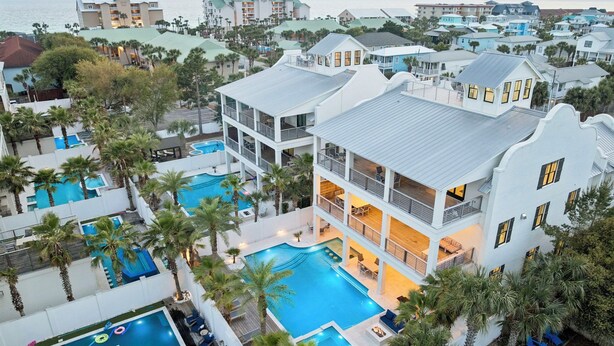 Un resort con varias piscinas, un edificio grande con balcones y vistas al océano.