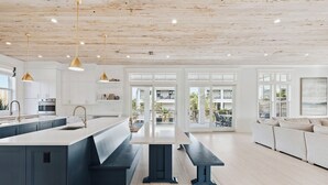 Una cocina moderna con una isla central, electrodomésticos integrados e iluminación colgante.