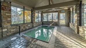 Ein Wellnessbereich mit Pool, Steinwänden und großen Fenstern.