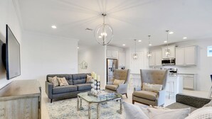 A modern living room with a sofa, armchairs, a glass coffee table, and a kitchen area with white cabinets and stainless steel appliances. - *NAPLES HOUSE WITH POOL near Marco Island (Naples)